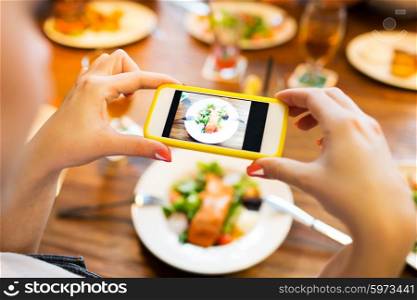 people, leisure, technology and internet addiction concept - close up of woman with smartphone photographing food at restaurant