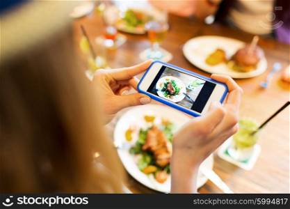 people, leisure, technology and internet addiction concept - close up of woman with smartphone photographing food at restaurant