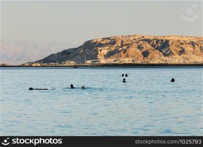 People lie on the water from the Dead Sea