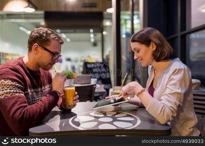 people, lifestyle and dating concept - happy couple with tablet pc computer and smoothie at cafe. happy couple with tablet pc and smoothie at cafe