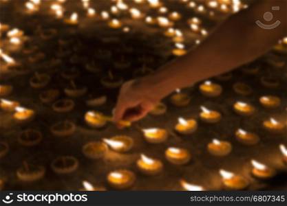 People light candle to pay respect to buddha relic at buddhist temple - blur image