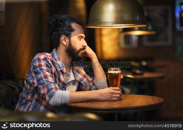 people, loneliness, alcohol and lifestyle concept - unhappy single man with beard drinking beer at bar or pub