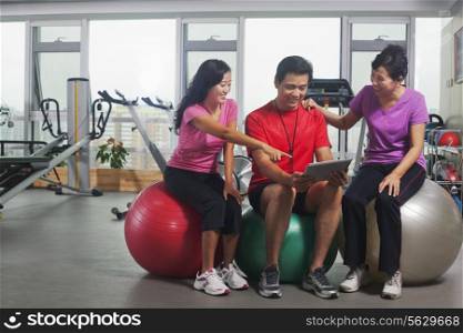 People looking at digital tablet in the gym
