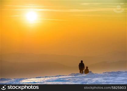 People looking at sunset in winter mountains covered with snow