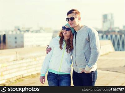 people, love and friendship concept - happy teenage couple walking in city