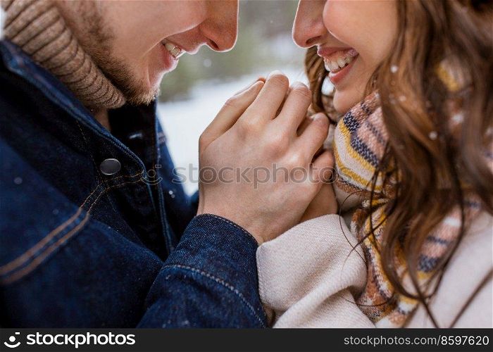 people, love and leisure concept - close up of happy man warming woman’s hands in winter park. happy man warming woman’s hands in winter park