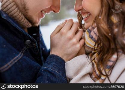 people, love and leisure concept - close up of happy man warming woman’s hands in winter park. happy man warming woman’s hands in winter park
