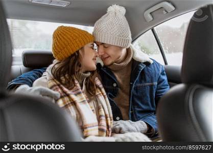 people, love and leisure concept - happy smiling couple hugging and rubbing noses on car back seat in winter. happy smiling couple on car back seat in winter