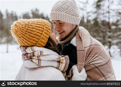 people, love and leisure concept - happy smiling couple looking at each other in winter forest. couple looking at each other in winter forest