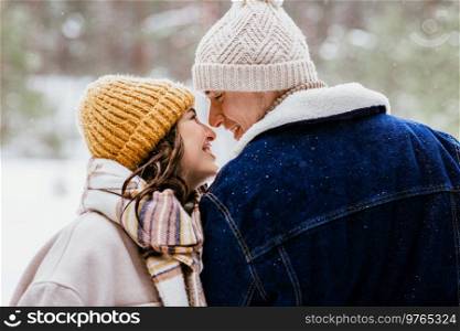 people, love and leisure concept - happy smiling couple looking at each other in winter forest. couple looking at each other in winter forest