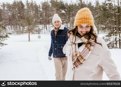 people, love and leisure concept - happy smiling couple walking in winter forest. happy smiling couple walking in winter forest