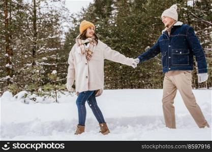 people, love and leisure concept - happy smiling couple walking in winter forest. happy smiling couple walking in winter forest