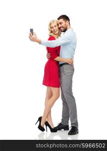 people, love, couple, technology and holidays concept - happy young woman and man taking selfie with smartphone and hugging