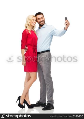 people, love, couple, technology and holidays concept - happy young woman and man taking selfie with smartphone and hugging