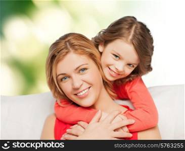 people, love, holidays, family and motherhood concept - happy mother and daughter hugging over green background