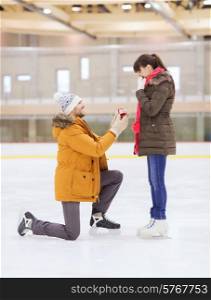 people, love, proposal, sport and leisure concept - happy couple with engagement ring on skating rink