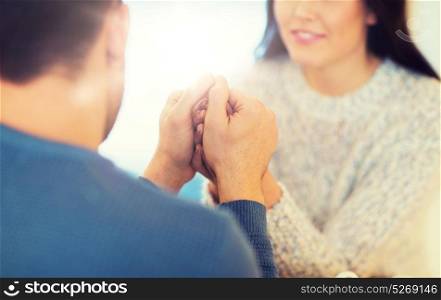 people, love, romance and dating concept - close up of couple drinking tea and holding hands at cafe or restaurant. happy couple holding hands at restaurant or cafe