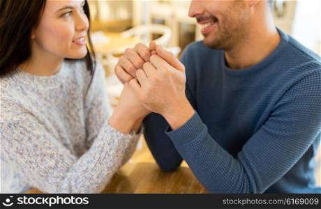 people, love, romance and dating concept - close up of couple drinking tea and holding hands at cafe or restaurant