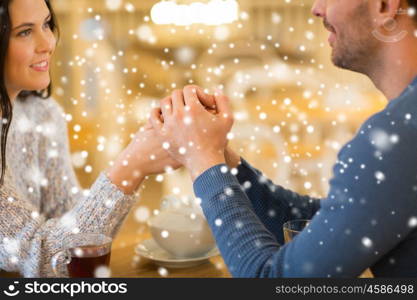 people, love, romance and dating concept - close up of happy couple drinking tea and holding hands at cafe or restaurant