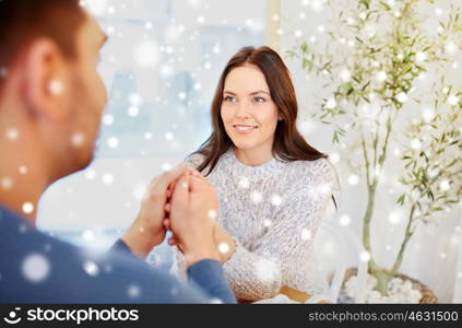 people, love, romance and dating concept - happy couple drinking tea and holding hands at cafe or restaurant