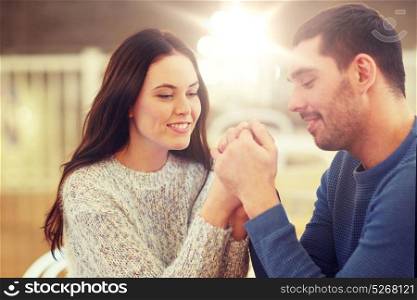 people, love, romance and dating concept - happy couple drinking tea and holding hands at cafe or restaurant. happy couple holding hands at restaurant or cafe