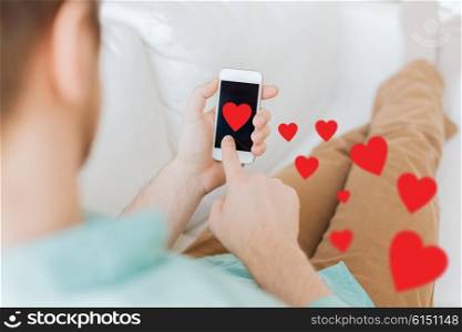 people, love, technology and communication concept - close up of man with smartphone and red hearts at home