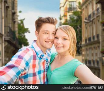 people, love, vacation, technology and summer concept - happy couple taking selfie with smartphone or camera over city street background