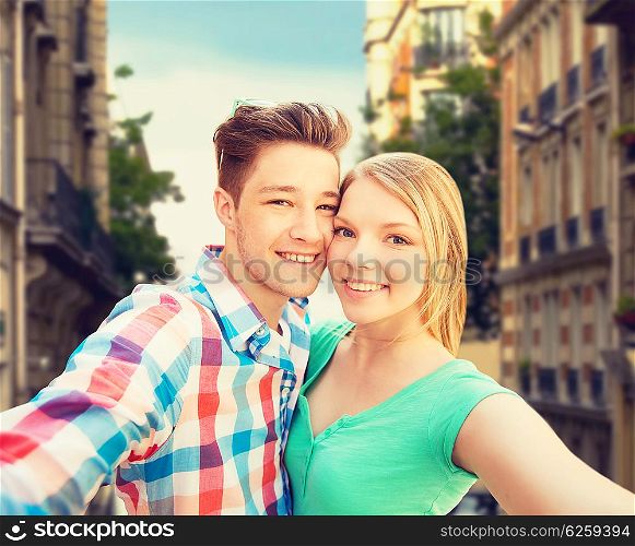 people, love, vacation, technology and summer concept - happy couple taking selfie with smartphone or camera over city street background
