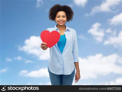 people, love, valentines day and health concept - happy african american young woman with red heart shape over blue sky and clouds background. happy african american woman with red heart shape