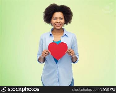 people, love, valentines day and health concept - happy african american young woman with red heart shape over summer green lights background. happy african american woman with red heart shape