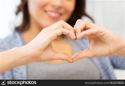 people, love, valentines day, charity and gesture concept - close up of happy young woman showing heart with hands