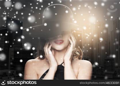 people, luxury and christmas concept - beautiful woman in black hat over dubai city double exposure background with snow