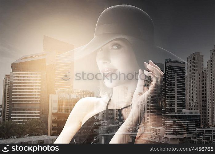 people, luxury and fashion concept - beautiful woman in black hat over dubai city with double exposure background