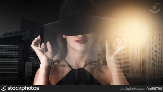 people, luxury and fashion concept - beautiful woman in black hat over dark over dubai city background with double exposure and highlight