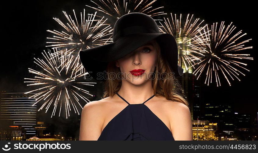 people, luxury and fashion concept - beautiful woman in black hat over night singapore city and firework background