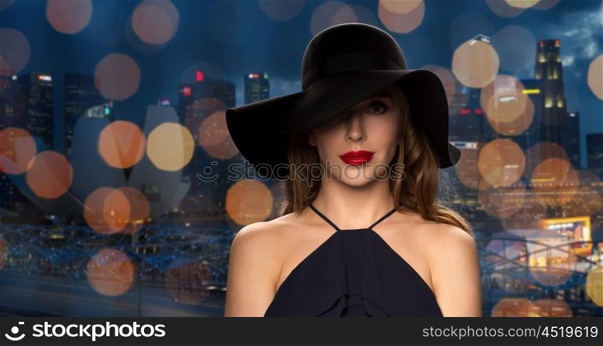 people, luxury and fashion concept - beautiful woman in black hat over night singapore city and lights background