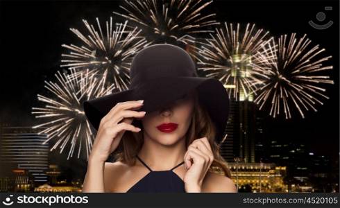 people, luxury and fashion concept - beautiful woman in black hat over night singapore city and firework background