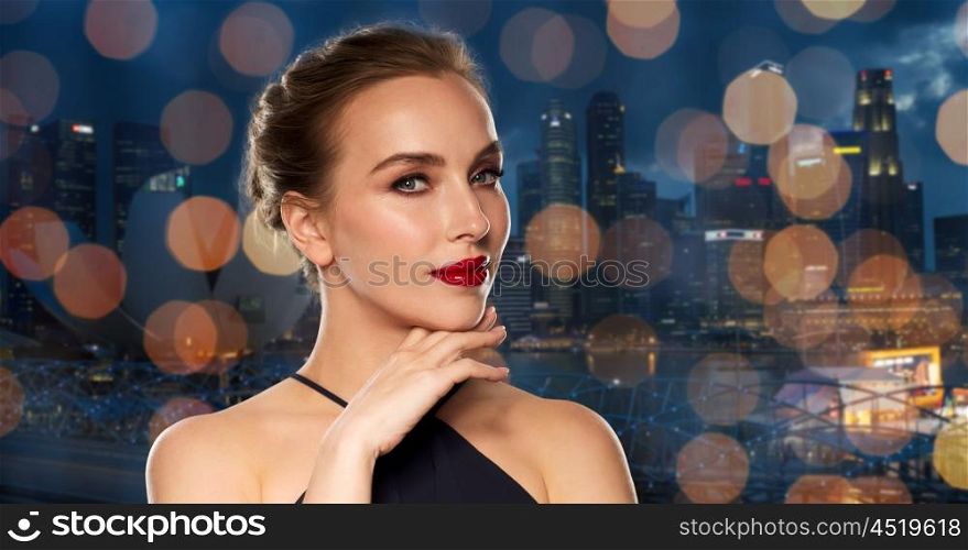 people, luxury and fashion concept - beautiful woman in black with red lips over night singapore city and lights background