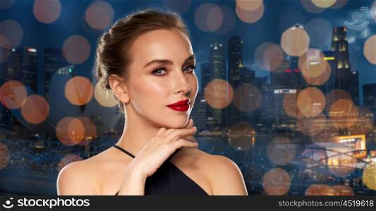people, luxury and fashion concept - beautiful woman in black with red lips over night singapore city and lights background