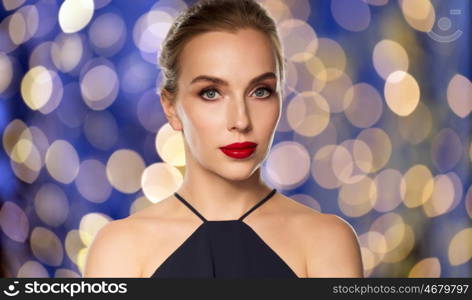 people, luxury and fashion concept - beautiful woman in black with red lips over blue holidays lights background