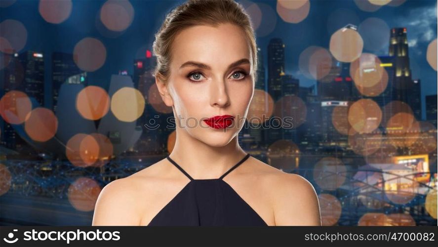 people, luxury and fashion concept - beautiful woman in black with red lips over singapore city and holidays lights background
