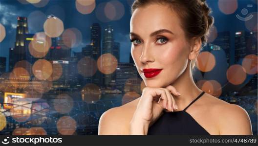 people, luxury and fashion concept - beautiful woman in black with red lips over singapore city with holidays lights background