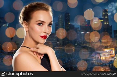 people, luxury and fashion concept - beautiful woman in black with red lips over singapore city and holidays lights background