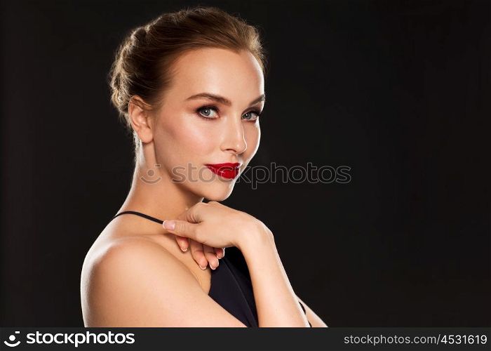 people, luxury and fashion concept - beautiful woman in black with red lips over dark background