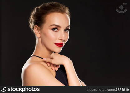 people, luxury and fashion concept - beautiful woman in black with red lips over dark background