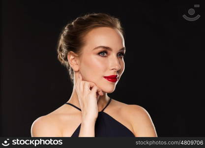people, luxury and fashion concept - beautiful woman in black with red lips over dark background