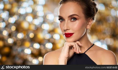 people, luxury and holidays concept - beautiful woman in black with red lips over lights background