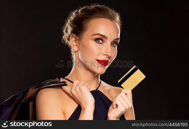 people, luxury and sale concept - beautiful woman with credit card and shopping bags over black background