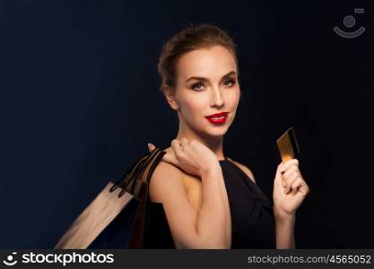 people, luxury and sale concept - beautiful woman with credit card and shopping bags over black background