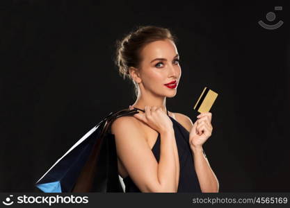 people, luxury and sale concept - beautiful woman with credit card and shopping bags over black background